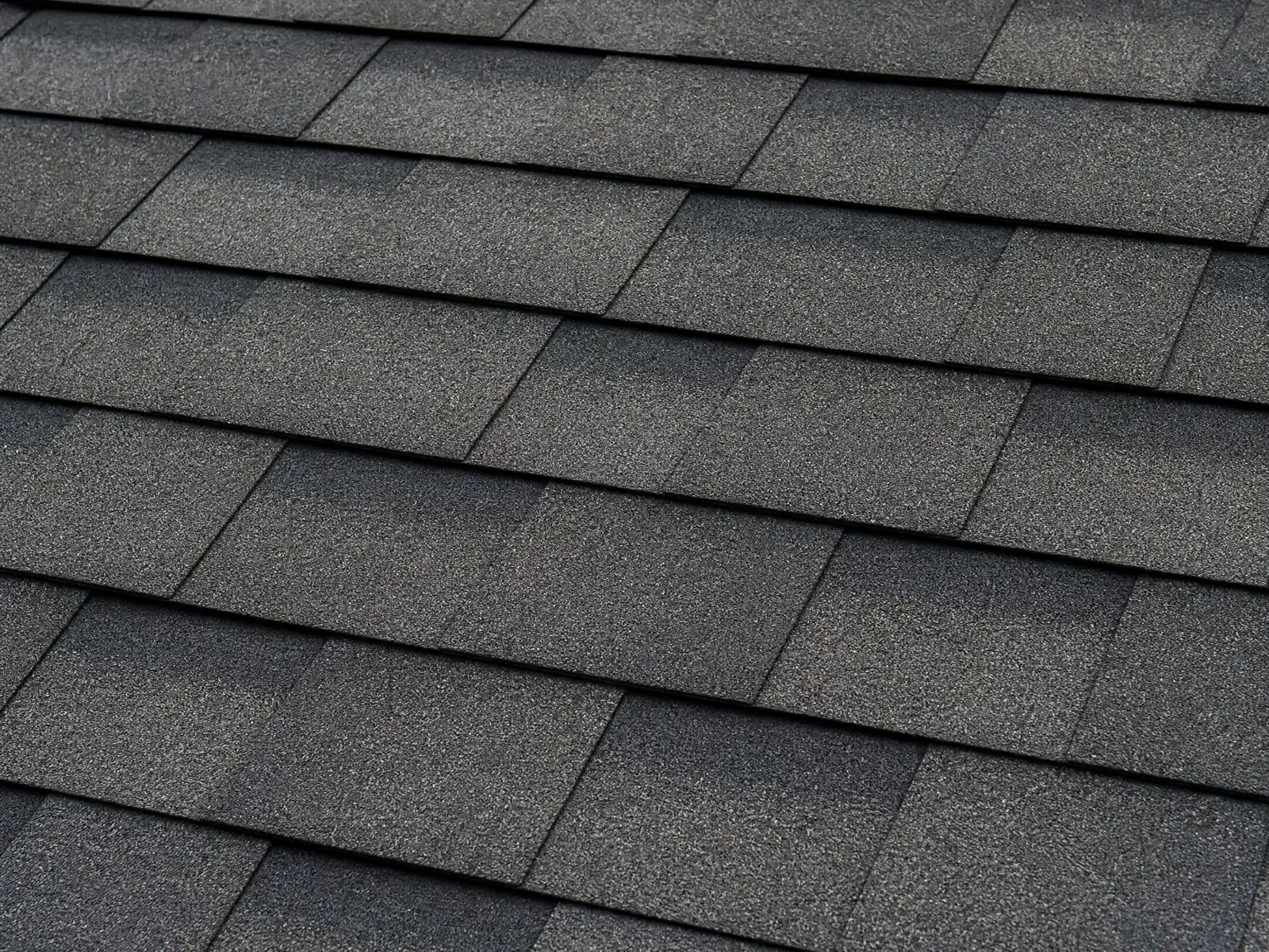 Close-up of charcoal architectural asphalt shingles in overlapping rows