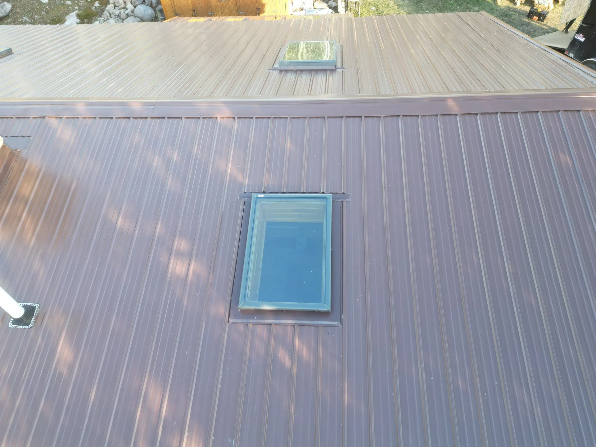 Skylight flashed into a brown standing seam metal roof — close detail of panel and trim work