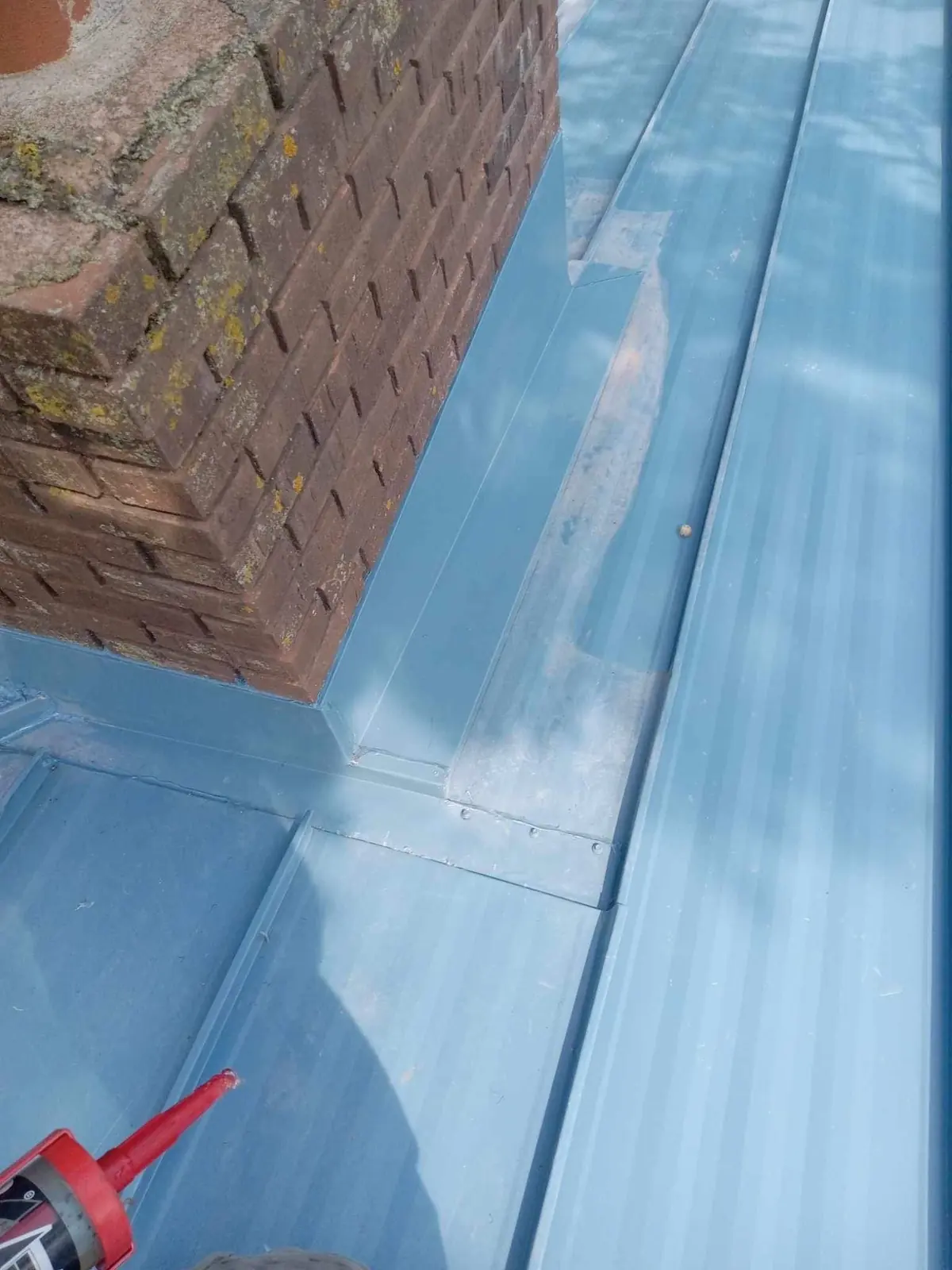 Standing seam metal roof with brick chimney and new step flashing, close detail