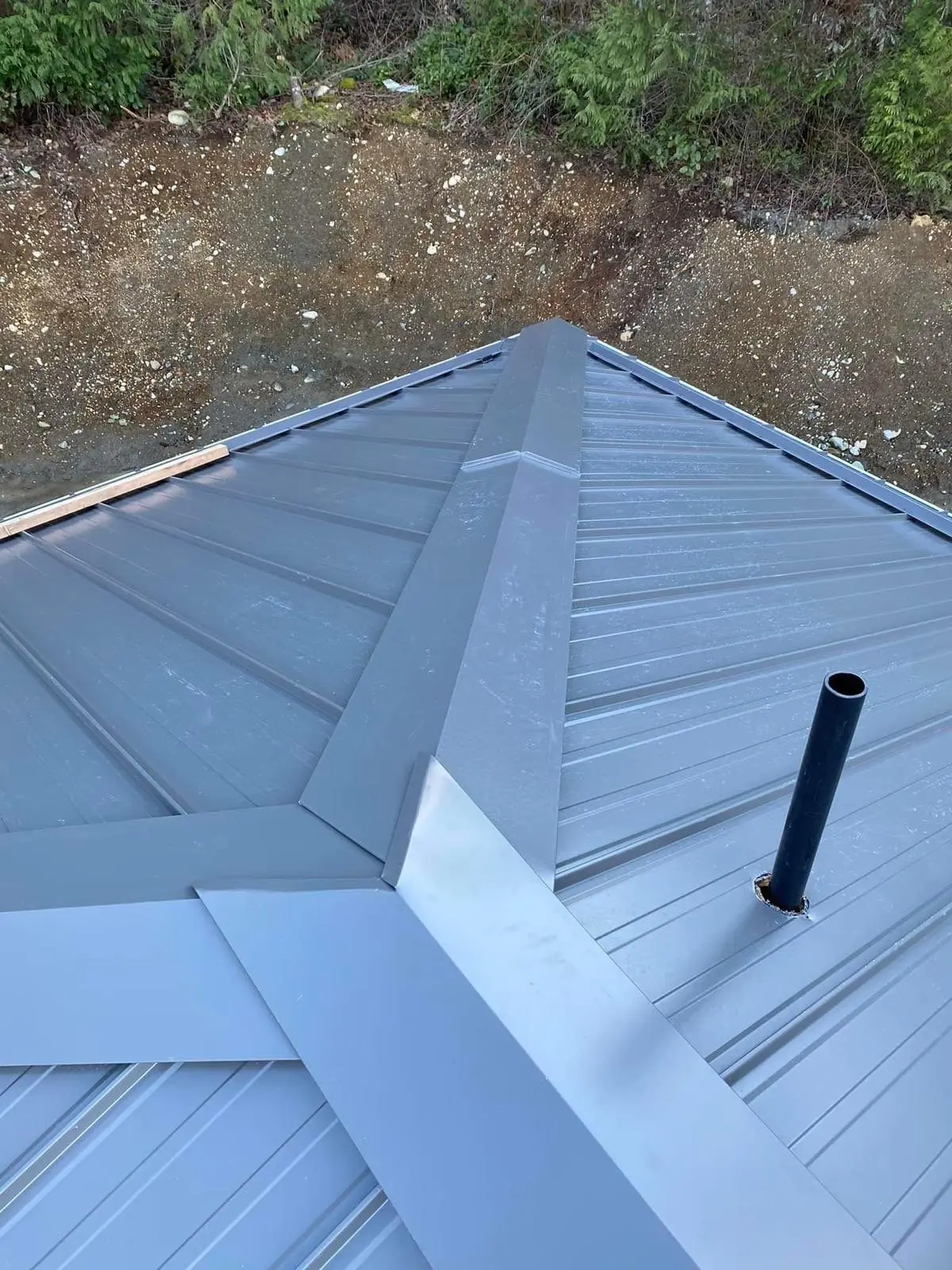 Aerial view of a pyramid-shaped standing seam roof over a round sunroom addition with divided-lite windows